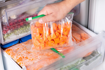 Bags with frozen vegetables in refrigerator. Frozen pumpkin cubes