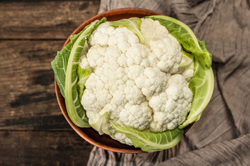 Beautiful cauliflower with green leaves in a ceramic bowl