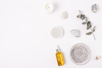 Cosmetic clay facial mask next to organic oil
