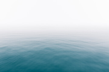 Heavy fog over calm ocean water surface - soft misty scenery on the sea with subtle ripples - Infinity - Calmness - serenity - lonely - quiet - moody background copy space