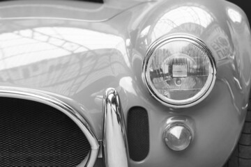 Black and white photo with round headlight of old retro car on black and white background in style...