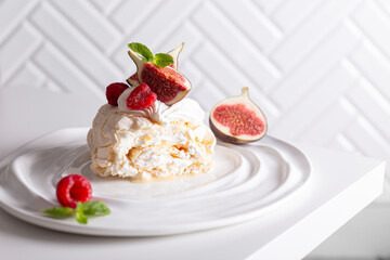 Beautiful meringue roll named Pavlova, decorated with figs and raspberries