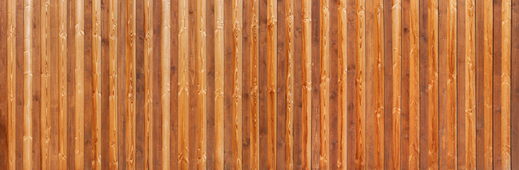 Braune, honigfarbene Panorama Holzwand aus vertikalen, gemaserten Brettern in verschiedenen Farbtönen