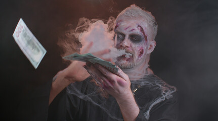 Portrait of sinister man in carnival costume of Halloween crazy zombie with bloody wounded scars face throwing money dollar cash banknotes. Horror theme of cosplay wounded undead, beast, monster