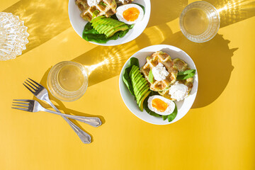 Belgian waffles with cream cheese, egg and avocado in a white plate. Healthy breakfast