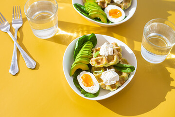 Belgian waffles with cream cheese, egg and avocado in a white plate. Healthy breakfast