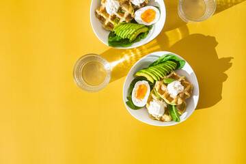 Belgian waffles with cream cheese, egg and avocado in a white plate. Healthy breakfast