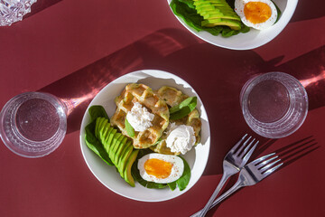 Belgian waffles with cream cheese, egg and avocado in a white plate. Healthy breakfast