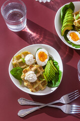 Belgian waffles with cream cheese, egg and avocado in a white plate. Healthy breakfast