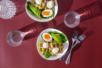Belgian waffles with cream cheese, egg and avocado in a white plate. Healthy breakfast
