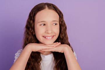 Photo of positive happy little girl beaming smile look empty space isolated on pastel purple background