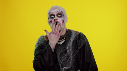 Oh my God, Wow. Scary man with Halloween zombie bloody wounded makeup raising hands in surprise...