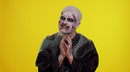 Sneaky cunning zombie man with makeup with wounds scars with tricky face gesticulating and scheming...