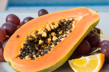 sweet papaya and red grapes in the mediterranean sunlight by the blue pool fruit close-up
