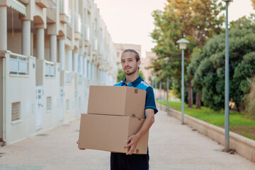 Delivery boy holding two boxes in the neighborhood
