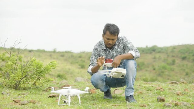 Drone videographer checking settings on mobile phone before flying - concept of drone photography and outdoor aerial filmmaking