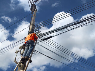 the technician on wooden ladder checking fiber optic cables  on electric pole at workplace with...