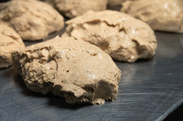 A piece of raw French bun dough against the background of other bun dough pieces. Raw craft bread dough
