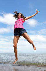 Obraz premium jump of a happy girl on the seashore in summer symbol of carefree joy