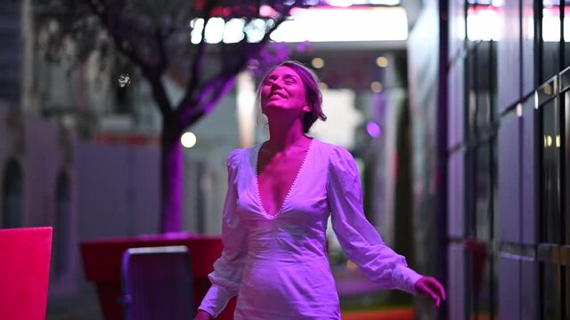 Woman in white dress posing in Cannes in purple lights, France