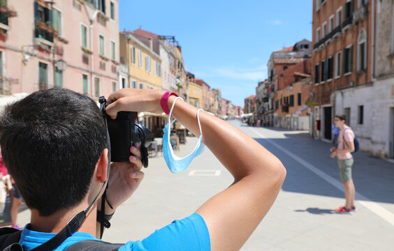 young boy taking pictures at the city of Venice with very few people during lockdown