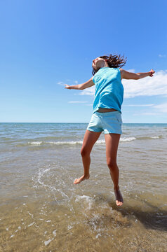 young girl by the sea making a big leap for joy