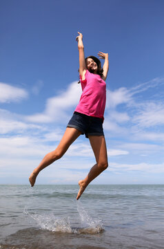 jump of a happy caucasian girl on the seashore in summer symbol of joy and carefree