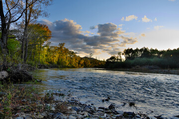 Autumn landscape of a clear mountain river with beautiful clouds at sunset.