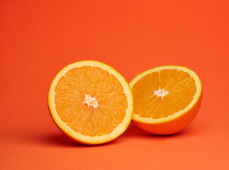 sliced fresh orange on vibrant, monochromatic, orange background. Saturated, warm colored.