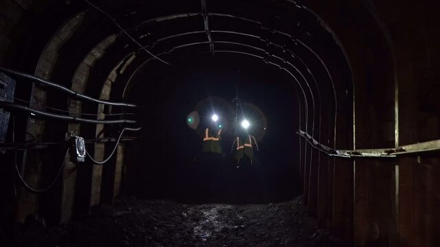 dusted tunnel in coal mine, silhouette of miner with flashlight