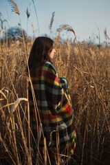 Girl walk in autumn pampas grass field in checkered warm plaid