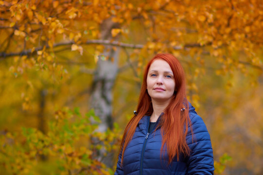 portrait of a life style woman with red hair in autumn against a background of colorful foliage