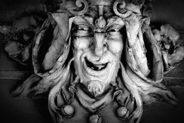 Monster face of aGreek antique god daimon of eager rivalry, envy, jealousy, and zeal Zelus (Zelos). Close up fragment of an ancient stone statue.  Horizontal image.