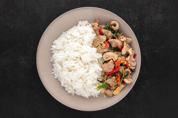 Khao Pad Ka Prao Kruang Nai Gai, Thai food, streamed rice with basil stir fried chicken offal, variety meats, pluck or organ meats on dark tone background, top view