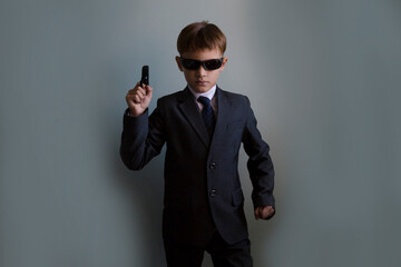 a schoolboy in a suit and tie laughs and sunglass depicts a super agent
