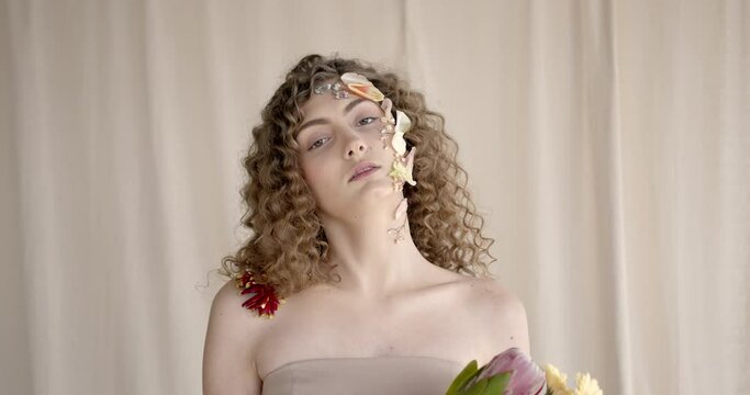Attractive woman with flowers on face pose in studio