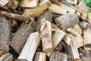 Fuel and heat source for the winter season.Preparing for the firewood heating season. Chopped firewood of different trees,outdoors.