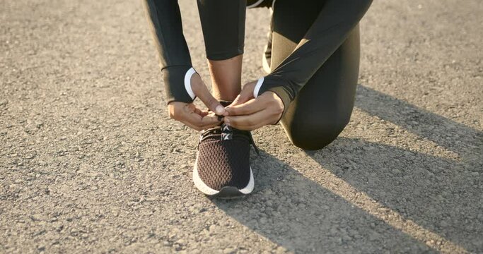 African American fit woman tiying shoelaces outdoors