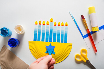 paper craft for kids. girl makes diy hanukkah candle holder. create art for children.