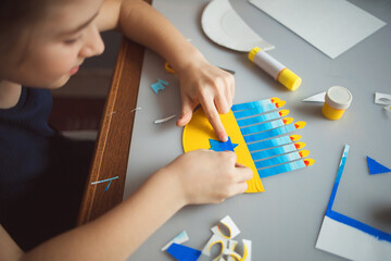 paper craft for kids. girl makes diy hanukkah candle holder. create art for children.