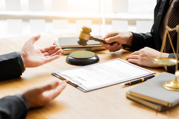 Male businessman and lawyer discussing legal matters and lawyers discuss contract documents sitting at a table. Legal concepts, advice, legal services. with a judge's hammer and golden scales on the d
