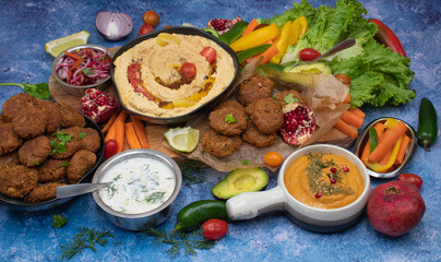 Mediterranean food spread with hummus, falafel, roasted pepper dip, yogurt sauce, crudites