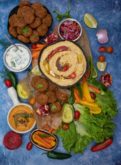 Mediterranean food spread with hummus, falafel, roasted pepper dip, yogurt sauce, crudites