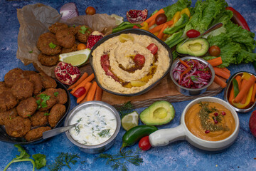 Mediterranean food spread with hummus, falafel, roasted pepper dip, yogurt sauce, crudites