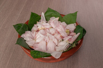 ceramic container filled with pink rose petals with leaves as decoration, aromatherapy object used in spa, texture details in studio