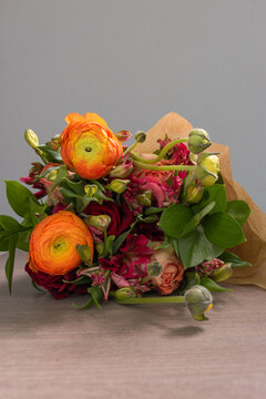 Detail Of The Head Of A Bouquet With Different Types Of Flowers And Leaves Wrapped In Decorative Paper, Beauty Of Nature, Colorful Valentine Gift To Show Love, In Studio With Wooden Textured Backgroun