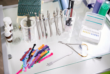 Various orthodontic tools and bracket placement card on desk in dental office. Multicolored...