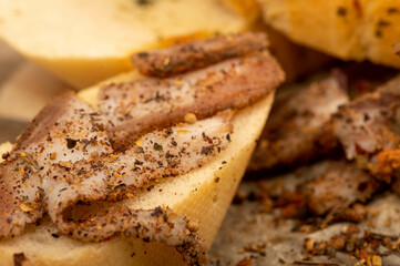 Sliced homemade bacon with pepper and sliced bread, close-up, selective focus.