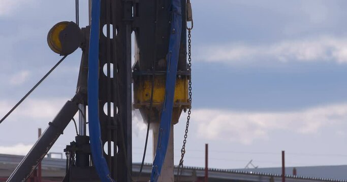 Excavation at a construction site, pile driving machine with rumble and smoke drives piles deep into the ground to ensure the strength of the foundation of the future structure 