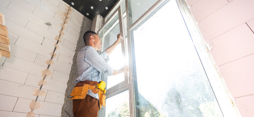 Construction worker installing window in house